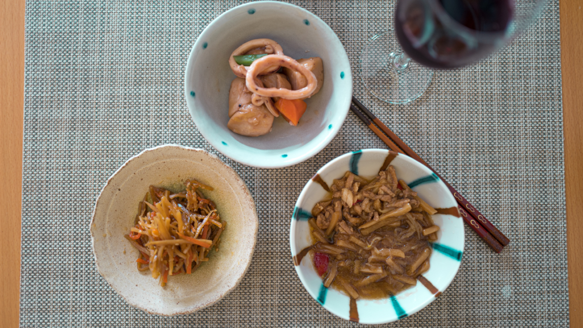 3 bowls of japanese food with a glass of red wine